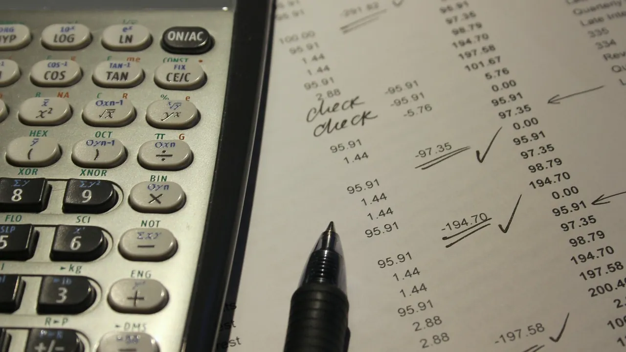 Colonnes de chiffres annotées au stylo, cochées et reprises à côté d’une calculatrice